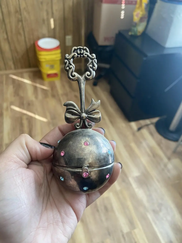 Что это за серебряный предмет в форме погремушки?